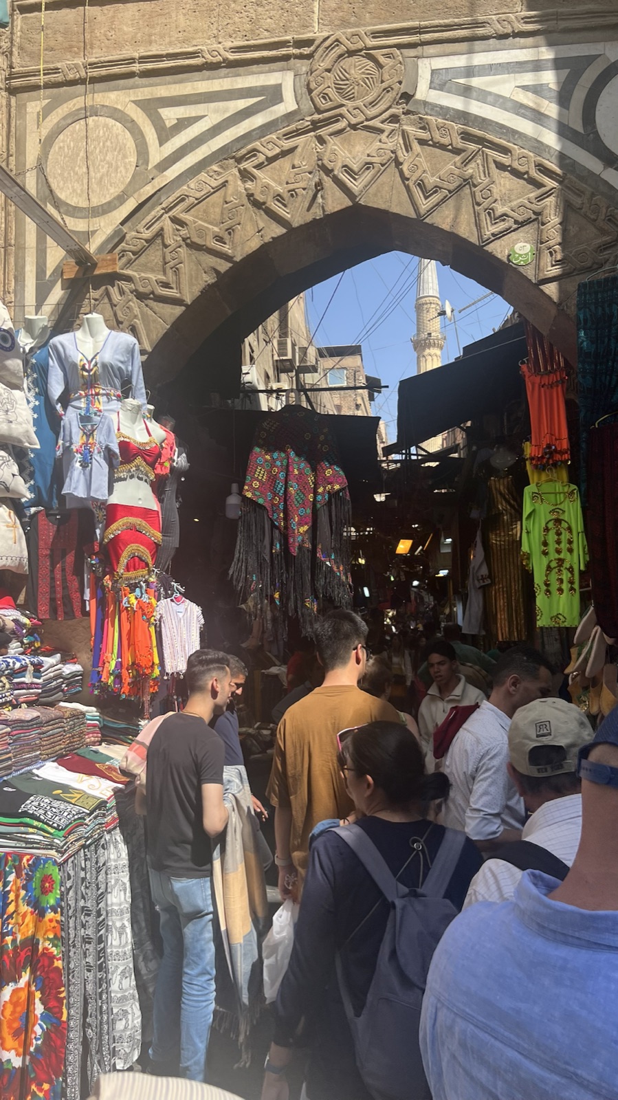 Lively market lane beneath a historic stone arch in Khan el-Khalili
